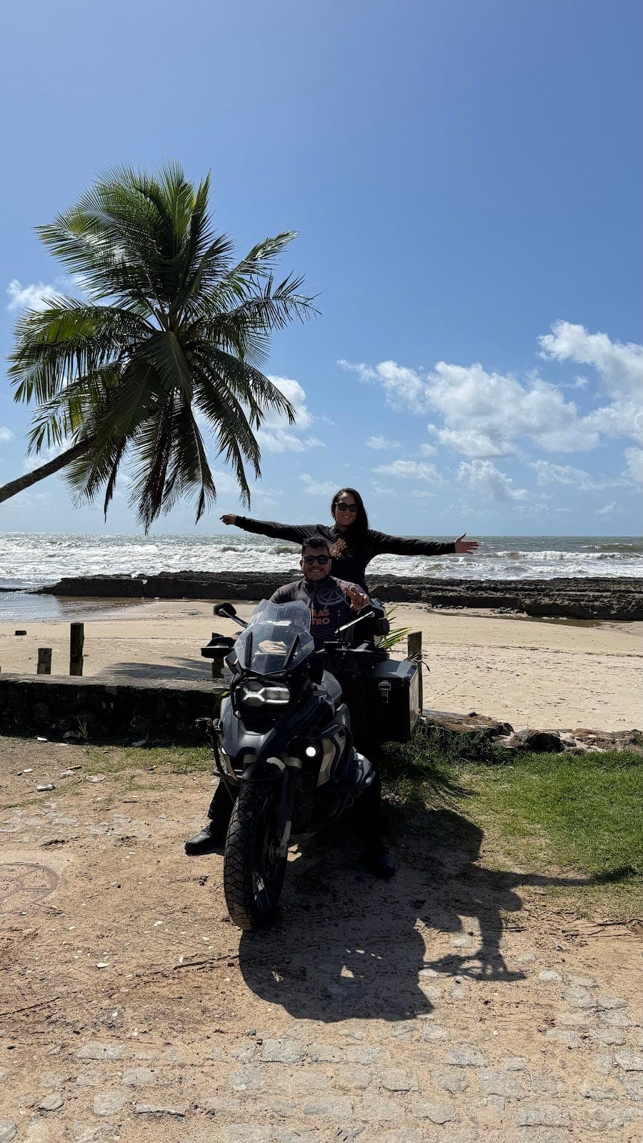 Na moto ao lado de um coqueiro na praia